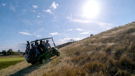 Fully loaded golf cart climbing a steep hill on a hilly golf course, illustrating real-world power system stress testing under maximum load.
