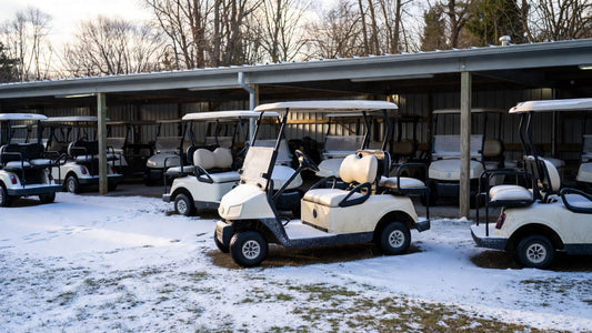 Golf carts stored in a cold winter garage at a golf course, illustrating the hidden impact of winter conditions on golf cart battery life.